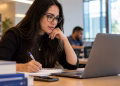 Profissional estuda pelo notebook e faz anotações, ilustrando as oportunidades de MBA gratuito da Enap.