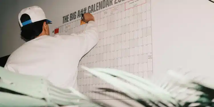 Homem escreve em calendário de parede: meses, dias da semana e estações do ano se escrevem com minúscula