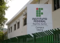 Fachada do Campus Vitória do Instituto Federal do Espírito Santo, com a placa da instituição e grades verdes, onde funciona o mestrado gratuito do Ifes em Tecnologias Sustentáveis