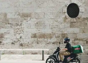 Entregador em scooter na rua: motorista e entregador de aplicativo podem ser nanoempreendedor pela regra dos 25%
