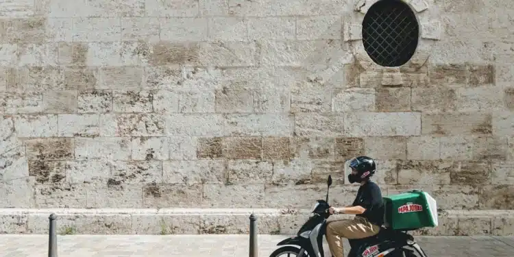 Entregador em scooter na rua: motorista e entregador de aplicativo podem ser nanoempreendedor pela regra dos 25%
