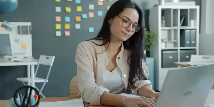 Jovem usa notebook em escritório, cena ligada a curso de informática com sistema, arquivos, internet e Excel