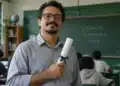 Professor com diploma de pós-graduação nas mãos, em sala de aula, representando a valorização salarial pela qualificação profissional.