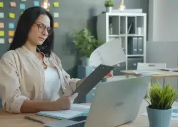 Mulher organiza documentos na mesa para a prova de títulos de concurso público