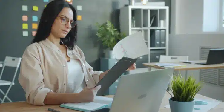 Mulher organiza documentos na mesa para a prova de títulos de concurso público