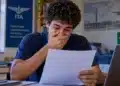 Jovem candidato confere resultado em papel, representando a divulgação dos aprovados na primeira etapa do Vestibular ITA 2027.