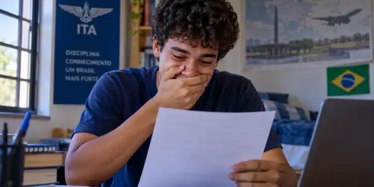 Jovem candidato confere resultado em papel, representando a divulgação dos aprovados na primeira etapa do Vestibular ITA 2027.