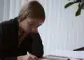 Jovem estudando com livro aberto na mesa durante a revisão para o Enem nos 15 dias antes da prova