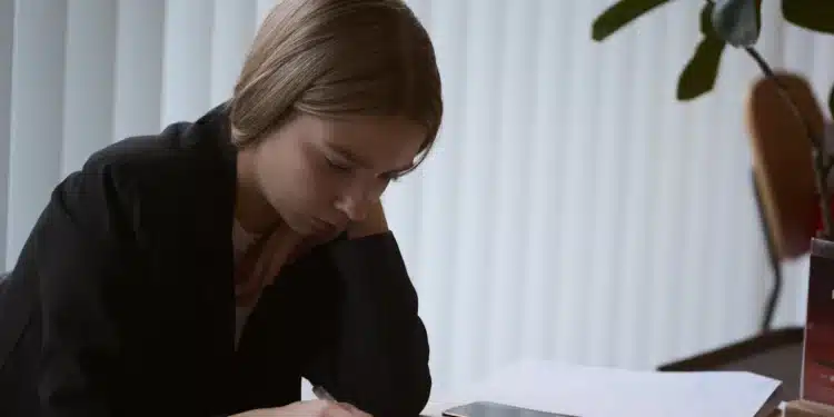 Jovem estudando com livro aberto na mesa durante a revisão para o Enem nos 15 dias antes da prova