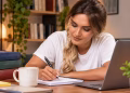 Imagem ilustrativa de mulher fazendo anotações em caderno ao lado de livros e notebook, em referência à dúvida sobre se a especialização exige trabalho de conclusão de curso
