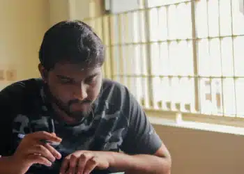 Homem escrevendo em uma folha sobre a mesa, exemplo de técnica de estudo em que a pessoa testa a própria memória