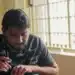 Homem escrevendo em uma folha sobre a mesa, exemplo de técnica de estudo em que a pessoa testa a própria memória