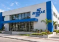 Edifício do Sebrae com fachada branca e azul, rampa e jardim ao lado em dia ensolarado, simbolizando as vagas de estágio do Sebrae.