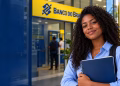 Jovem universitária negra sorrindo, segurando cadernos, diante de agência do Banco do Brasil, simbolizando as vagas de estágio para estudantes do ensino médio.