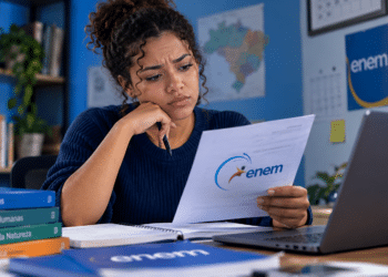 Estudante analisa documento do Enem, representando dúvidas sobre a validade das notas para ingresso no ensino superior.